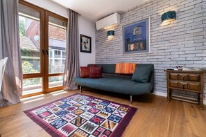 Open-concept space with wooden floors, a sleek kitchen with neutral cabinets and a tiled backsplash, a dining table with white chairs, and a cozy TV area. Bright and modern, offering a comfortable and stylish atmosphere for guests
