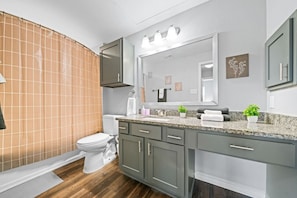 This bright and welcoming bathroom invites you to freshen up in comfort. Enjoy the forest-inspired shower curtain that adds a calming touch to your routine, complemented by the cozy rug underfoot and sparkling clean fixtures.