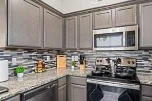 Cook with ease in this well-equipped kitchen featuring stainless steel appliances, ample cabinetry, and a stylish backsplash. Whether you're brewing coffee or preparing a gourmet meal, this space is designed for functionality and style, making every meal