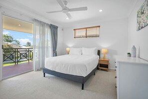 Your serene primary retreat awaits upstairs, complete with a queen bed, floral artwork, and warm lighting. Enjoy direct access to a spacious balcony for morning coffee or an evening escape.