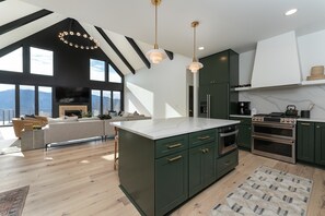 Luxury open floor plan with living, dining, and kitchen areas on the main level with floor-to-ceiling mountain views. Note: The fireplace is NOT usable.