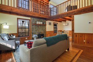  A spacious living area with a couch, fireplace, and an open loft above.