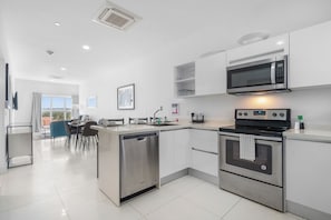 Prepare meals in this bright & stylish kitchen featuring stainless steel appliances - Convenient island with seating makes this space perfect for casual dining or a quick coffee - Designed for functionality & comfort, it's a home away from home