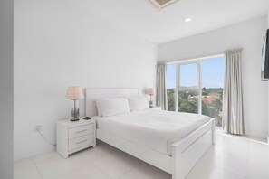 Wake up to stunning views and natural light in this cozy, inviting king size bedroom - Relax in comfort with plush bedding, a wall-mounted smart TV, and serene surroundings - Peaceful retreat to recharge and enjoy the beauty of your tropical escape