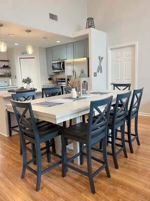 Counter height kitchen table with 8 chairs and two additional at the counter.