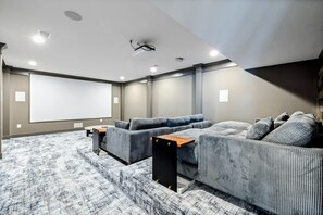 A dedicated home theater with tiered seating, plush couches, a large projector screen, and cozy cinema-themed decor for an immersive movie experience.