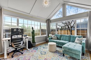 The bright sunroom den is also the ultimate office with ergonomic desk and tools
