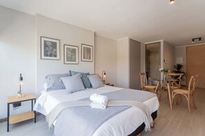 Relax in this serene bedroom with modern decor and a cozy dining nook, perfect for unwinding after a day of exploring.