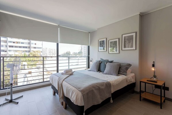 Relax in this bright, modern bedroom with city views and stylish decor, perfect for a restful stay.