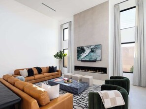 Living room with 85-inch smart TV and electric fireplace. 