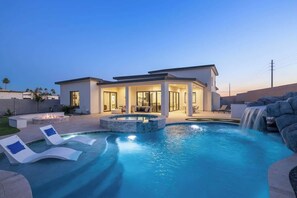 Spacious backyard with large pool, hottub, and waterslide along with chaise loungers. Massive firepit with seating. Cool putting green w/ putters and balls. Chain swing on patio with other seating and dining area. Gas BBQ grill.