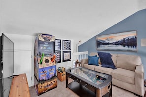 Loft game room with endless entertainment! 🎮🕹️ Enjoy board games, arcade fun, and a pull-out couch for extra sleeping space. Perfect for relaxing after a day of adventure!