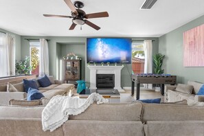 Relax and play in style with a spacious living room featuring large seating, a smart TV, foosball table, shuffleboard, and a card game table!