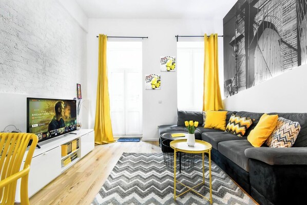Relax in this stylish and cozy living room with vibrant yellow accents and a Smart TV for your entertainment. Perfect for unwinding after exploring Sofia. Book your stay now!