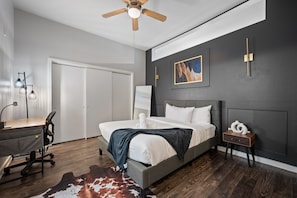 Spacious bedroom with black accent wall, workspace, and ceiling fan