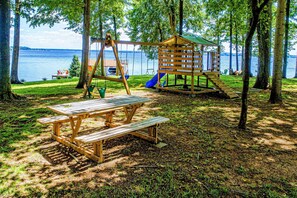 Family-friendly outdoor space with a playground, swing set, picnic table, and scenic lake views.