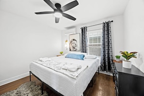 Bedroom: Featuring a sleek ceiling fan, modern furnishings, and a cozy bed with plush textures, this bedroom is designed for comfort and relaxation.