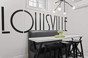 Dining Area: Dine in style with this chic black-and-white aesthetic featuring a bold “Louisville” mural and a modern chandelier.