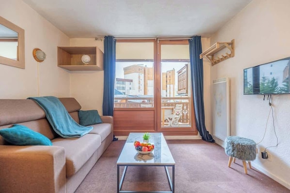 Salon chaleureux avec accès au balcon avec vue sur la station et la vallée.