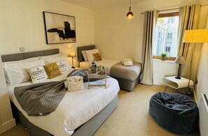 Bright and inviting bedroom featuring a comfortable double bed and single bed with plush linens, ideal for a restful and relaxing stay