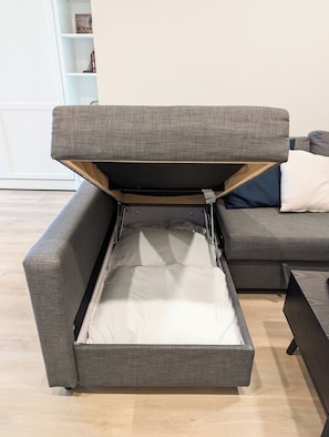 Sheets, pillows, and duvet are stored in compartment under the chaise cushions.