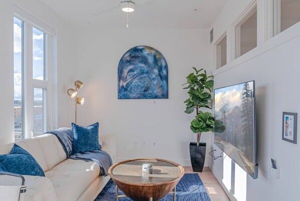 Beautifully designed living room. 65" TV, comfy sofa and amazing views of mountains and city skyline.