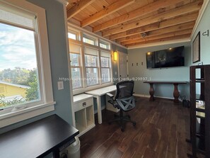 Studio/office space with 2 desks, small bookshelf, and big screen TV