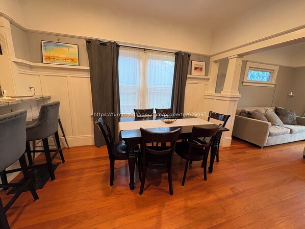 Countertop with 3 bar stools, dining table with 6 chairs, and living room