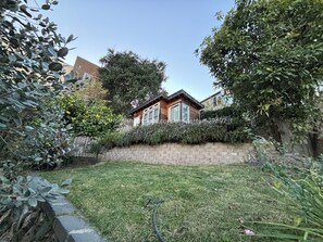Terraced backyard with grass, fruit trees, herbs, and separate studio/office spa
