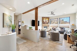 The living room features a gas fireplace with stunning wood beams, cathedral ceilings, and a remote-operated gas fireplace. Huge windows let in natural light and showcase breathtaking Red Rock views.