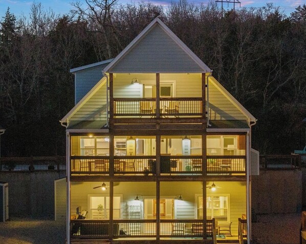 - Beautiful three level lakeview home glows warmly under evening skies
- Multiple decks provide plenty of space to gather, grill, or unwind under the stars
- The home's welcoming ambiance shines through, even before you walk in
