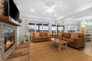 - Inviting living room featuring plush leather sofas and a stunning stone fireplace
- Large windows flood the space with natural light and frame picturesque lake views
- Perfect for family game nights, movie marathons, or sipping wine by the fire