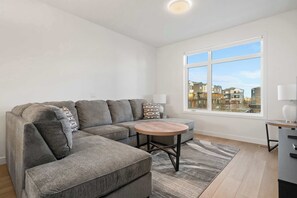 The room is tastefully furnished with a plush sectional sofa, coffee tables and a Smart TV