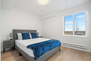 This ground level guest bedroom is a welcoming space with natural light, and a queen sized bed