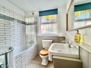 Traditionally styled with a modern twist, a bathroom with a shower over