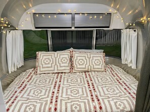 Drift off in comfort under twinkling lights in the cozy bedroom area. Featuring a plush bed with all cotton linens and panoramic windows, it’s the perfect retreat for restful nights and serene mornings.