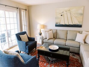 Sunlit living room with comfortable seating, large windows, and coastal-inspired decor.
