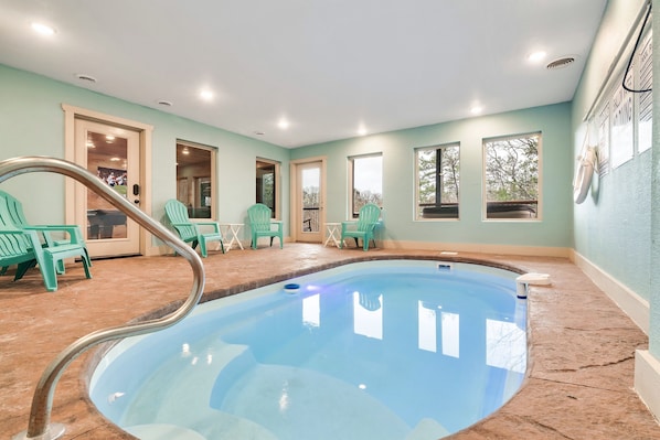 Private heated pool inside the cabin with tables, chairs, and towels included.