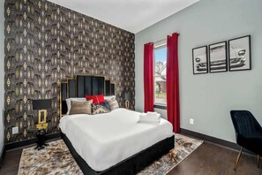 Sleep in style in this glam Art Deco-inspired bedroom featuring bold gold accents, plush velvet decor, and a luxe queen bed. Pops of red and vintage art complete the chic, comfortable vibe—perfect for a restful Nashville getaway.

