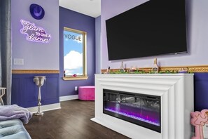 Step into glam! This bold, purple lounge features a cozy fireplace, neon vibes, and chic decor. Perfect for a stylish escape or a girl's getaway with serious attitude.