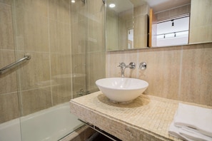 Experience a clean and modern bathroom with a stylish glass shower and elegant mosaic countertop.