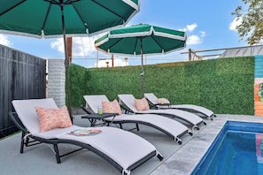 Imagine a tranquil poolside setting featuring four comfy lounge chairs arranged in a relaxed, inviting manner. Each chair is generously cushioned with plush, weather-resistant fabric in a soft, neutral tone.