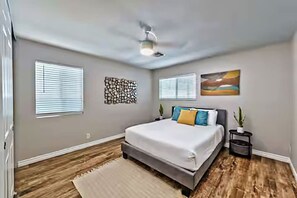 Bedroom #2 includes a Queen-sized bed with white linens and colorful pillows, a white ceiling fan, a sliding closet with a pack and play, and a black nightstand.