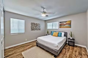 Bedroom #2 includes a Queen-sized bed with white linens and colorful pillows, a white ceiling fan, a sliding closet with a pack and play, and a black nightstand.