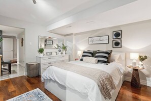 Enjoy a restful night on the queen-sized bed with luxurious linens and plush pillows. The room features a spacious dresser and bedside tables with easy-to-reach lamps, perfect for storing your essentials and setting the mood for relaxation.