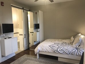 Bed facing TV and bathroom with door