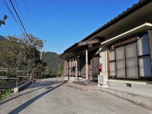 In front of the entrance. There is a parking lot in front.