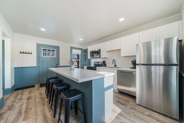 Sleek kitchen design with plenty of storage and a central island for dining. Stainless steel appliances include a microwave, oven, dishwasher, and coffee maker. Features a view of the backyard for a pleasant cooking experience.