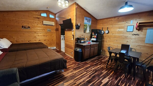 Living space with 2 queen beds, sofa, and kitchenette with dinette set.