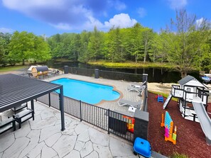 Poolside view with full lounge setup and forest beyond.
